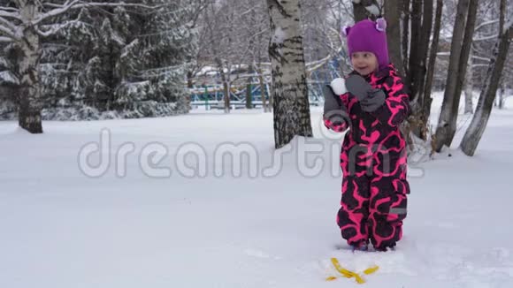 一个穿着粉红色冬季连衣裙的小女孩玩雪视频的预览图