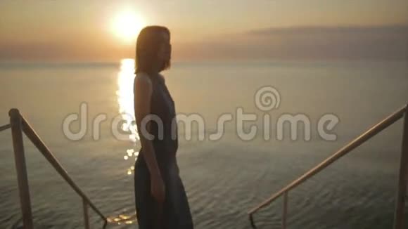 在日落或日出时美丽的年轻女子走在船上或码头上视频的预览图