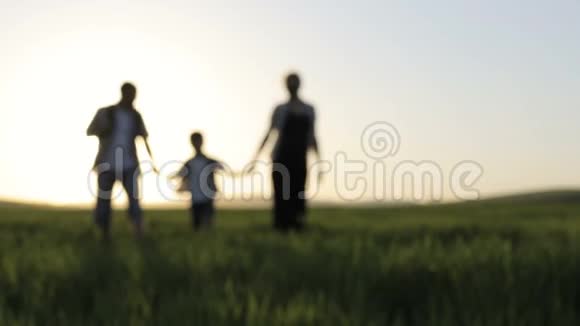 日落时分父亲母亲和儿子在田野上散步视频的预览图