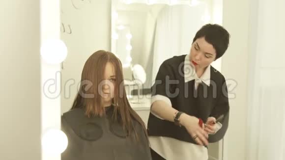 发型师在美发沙龙用剪刀梳理剪长发关闭理发师做女性理发视频的预览图