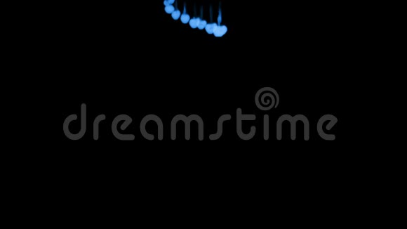 许多黑色背景上的蓝色荧光墨水从上到下溶解在水中侧面视频的预览图
