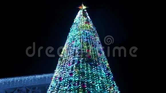在大雪纷飞的冬夜大圣诞树上装饰着发光的花环相机飞来飞去视频的预览图