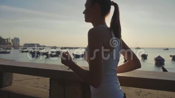 运动的年轻女子在日出时慢动作在海滨慢跑视频的预览图