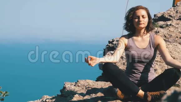 美丽的年轻女子练习瑜伽和在户外的位置在一个令人难以置信的悬崖顶部设置视频的预览图