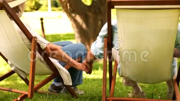一对退休夫妇手牵手坐在躺椅上视频的预览图