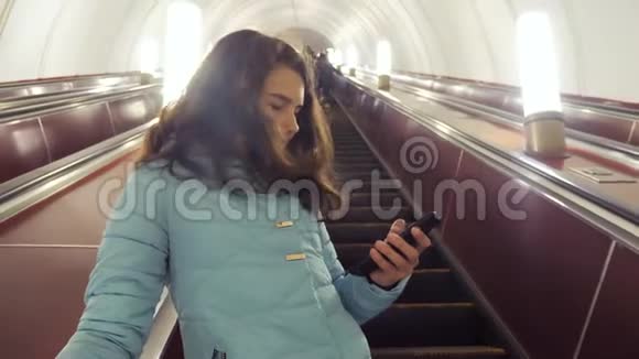 少女在地下地铁乘坐自动扶梯手持智能手机小女孩黑发女儿生活方式视频的预览图