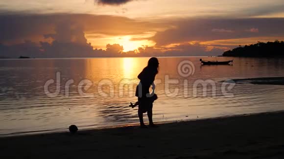 日落时分带着孩子的女孩在海滩上散步和玩耍视频的预览图