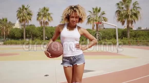 年轻女子用篮球摆姿势视频的预览图