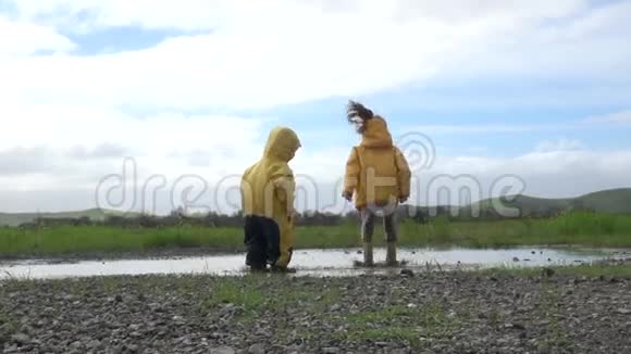穿雨靴的孩子们在水坑里快乐地跳跃视频的预览图