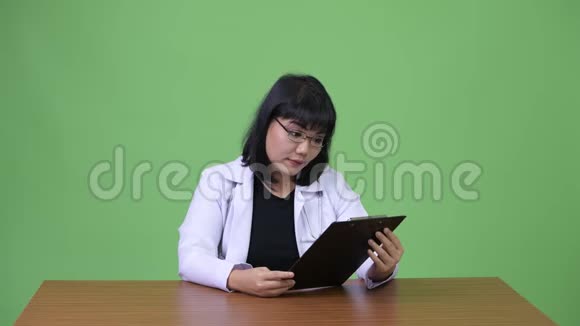 美丽的亚洲女医生阅读剪贴板视频的预览图