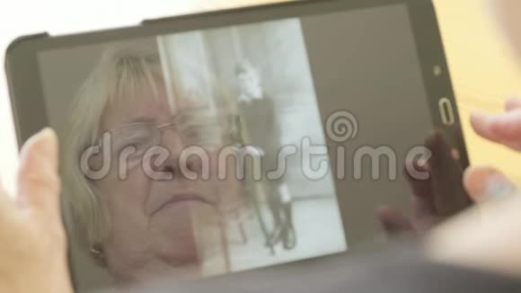 一位年长妇女在平板电脑上看旧照片的反映视频的预览图