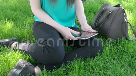 有平板电脑的女学生坐在草地上视频的预览图