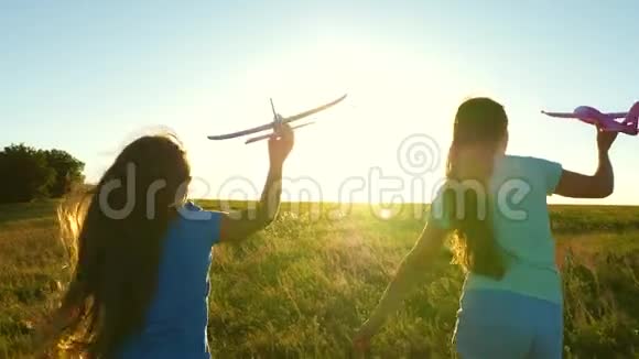 快乐的童年概念飞行的梦想两个女孩在日落时玩玩具飞机以太阳为背景的儿童视频的预览图