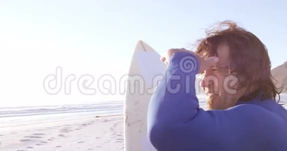 冲浪者在沙滩上用冲浪板遮挡眼睛视频的预览图