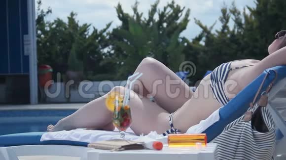 美丽的黑发女性在沙滩椅上放松晒黑视频的预览图