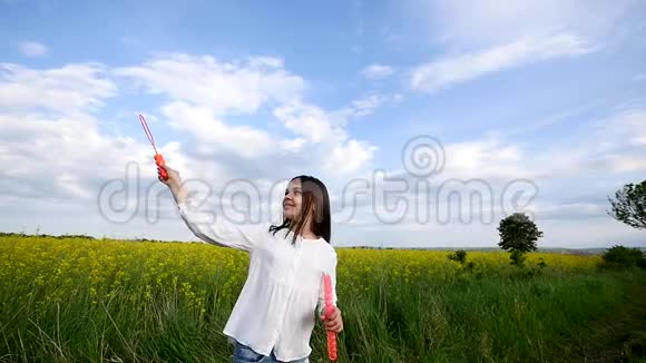 夏天快乐的小女孩在绿色草地上玩肥皂泡视频的预览图