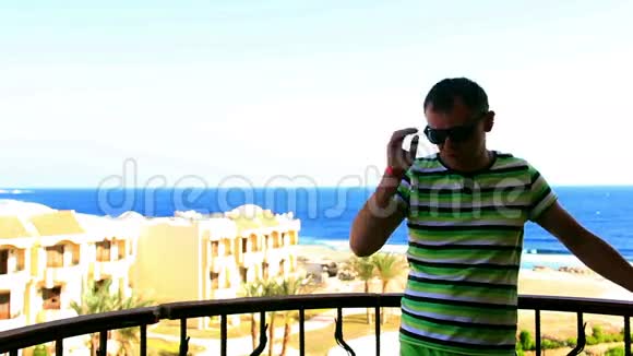 有海景的人在阳台上戴太阳镜视频的预览图