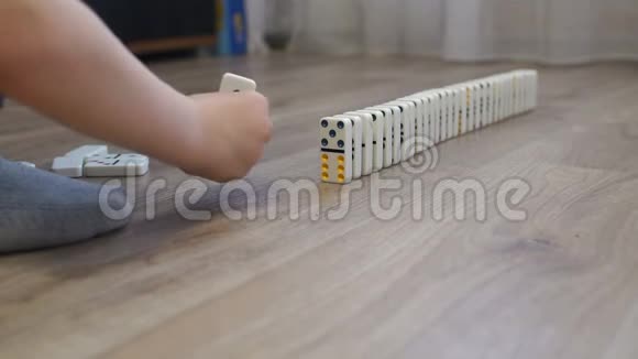 一个小男孩在房子的地板上玩多米诺骨牌的特写镜头视频的预览图