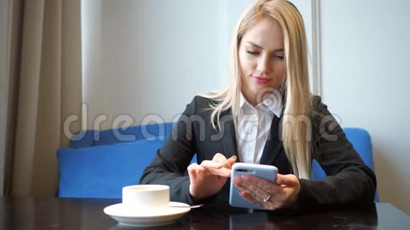 一个穿西装带电话的金发女孩坐在咖啡馆的桌子旁视频的预览图