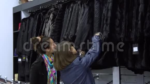 两个年轻漂亮的女孩在一家时尚的精品店里挑选衣服女孩们仔细地看着衣服并检查它视频的预览图
