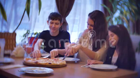 一家群孩子在咖啡馆里吃披萨青少年在室内咖啡厅吃快餐慢动作视频的预览图