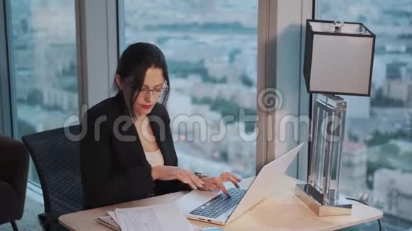 一位年轻的女士坐在一间现代化的办公室里一边用笔记本电脑工作视频的预览图