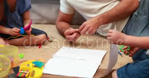 快乐的兄弟姐妹和父母一起在地毯上做工艺品视频的预览图