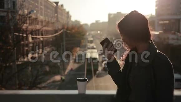 美丽的女孩在城市桥上使用智能手机视频的预览图
