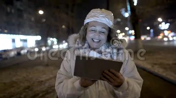 快乐的女人在晚上的街道上用垫子行走视频的预览图