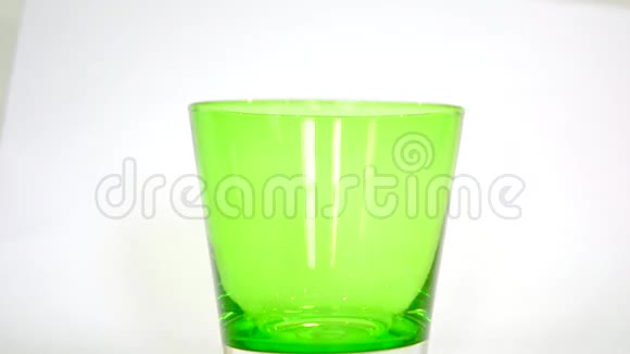 纯饮用水将绿色玻璃在白色背景下变成蓝色视频的预览图