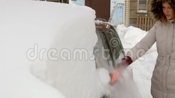 女青年在暴风雪后用刮泥机清洗汽车视频的预览图