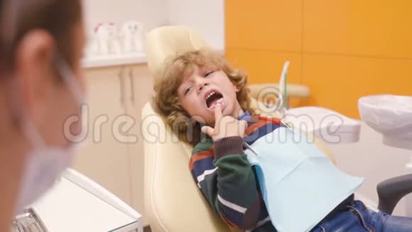 一个卷发在牙科椅上的小男孩视频的预览图