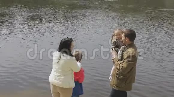 在温暖的天气里家人在河岸散步视频的预览图