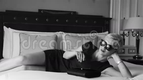美丽的金发商务女性穿着紧身短裙戴着墨镜豪华酒店客房放松休息时尚潮流视频的预览图