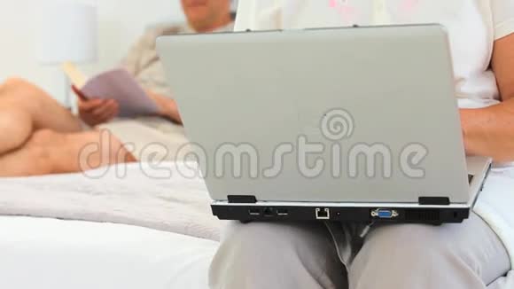 她丈夫正在看书的时候正在用笔记本电脑工作视频的预览图