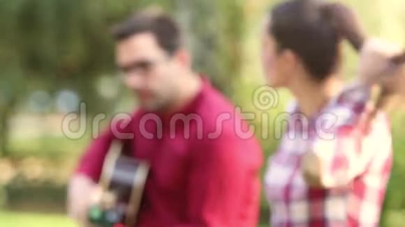 年轻人弹吉他唱歌而美女则坐在他旁边视频的预览图