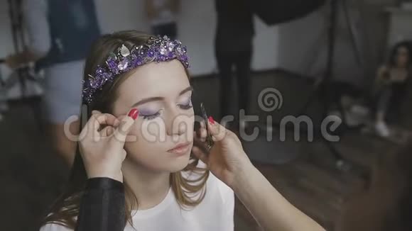 化妆师在照相馆为一个非常漂亮的女孩做专业的化妆视频的预览图