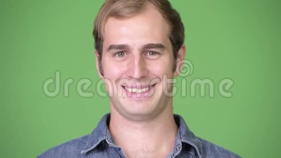 年轻的快乐男人在绿色的背景下微笑视频的预览图