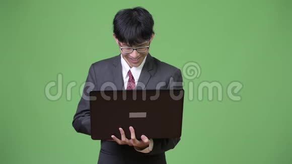 年轻快乐的亚洲商人微笑着使用笔记本电脑视频的预览图