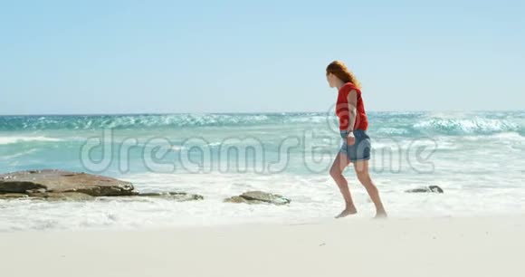 在阳光明媚的4k天在海滩上散步的女人视频的预览图
