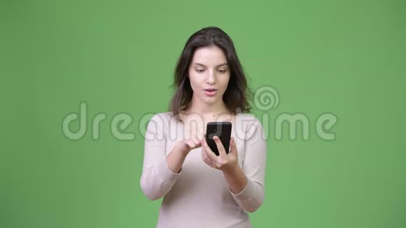 年轻漂亮的女人用电话得到好消息视频的预览图