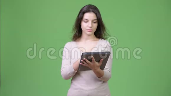 年轻快乐的美女在用数码平板电脑思考视频的预览图