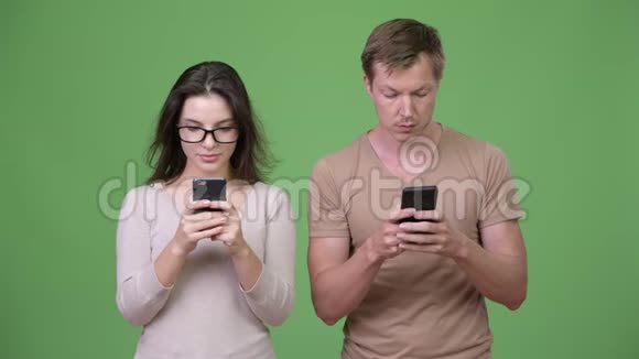 年轻夫妇在绿色背景下一起使用手机视频的预览图