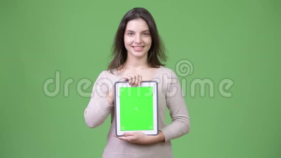 年轻快乐的美女微笑着展示数码平板电脑视频的预览图