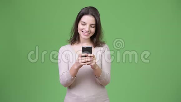 年轻快乐的美女在绿色背景下使用电话视频的预览图