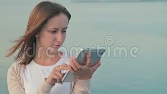 日出时在游轮甲板上使用平板电脑的女人视频的预览图