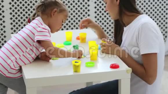 年轻漂亮的妈妈和可爱的小女儿一起玩泥塑视频的预览图