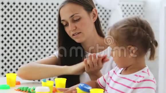 年轻漂亮的妈妈和可爱的小女儿一起玩泥塑视频的预览图