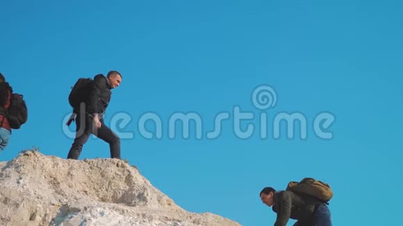团队合作帮助商务旅行剪影概念一群游客伸出援手帮助攀登悬崖上的山视频的预览图