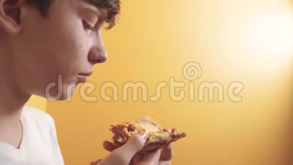 披萨快乐的青少年男孩吃一片披萨的概念青少年生活方式男孩饿了吃一片披萨慢动作视频的预览图